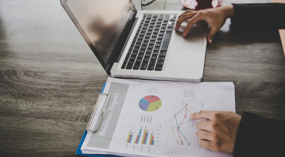 In this visual, we find ourselves in a professional setting—a blend of digital and analog tools. The centerpiece is a laptop, its trackpad diligently navigated by one hand. The other hand points to a printed document titled “Business & Report.” This document isn’t your run-of-the-mill memo; it’s a colorful compilation of charts and graphs, a visual symphony of data. Now, let’s zoom in on the star of the show: Prima Consulting’s Delta IFRS 17 Software. Specifically, we’re peeking at its Actuarial Module