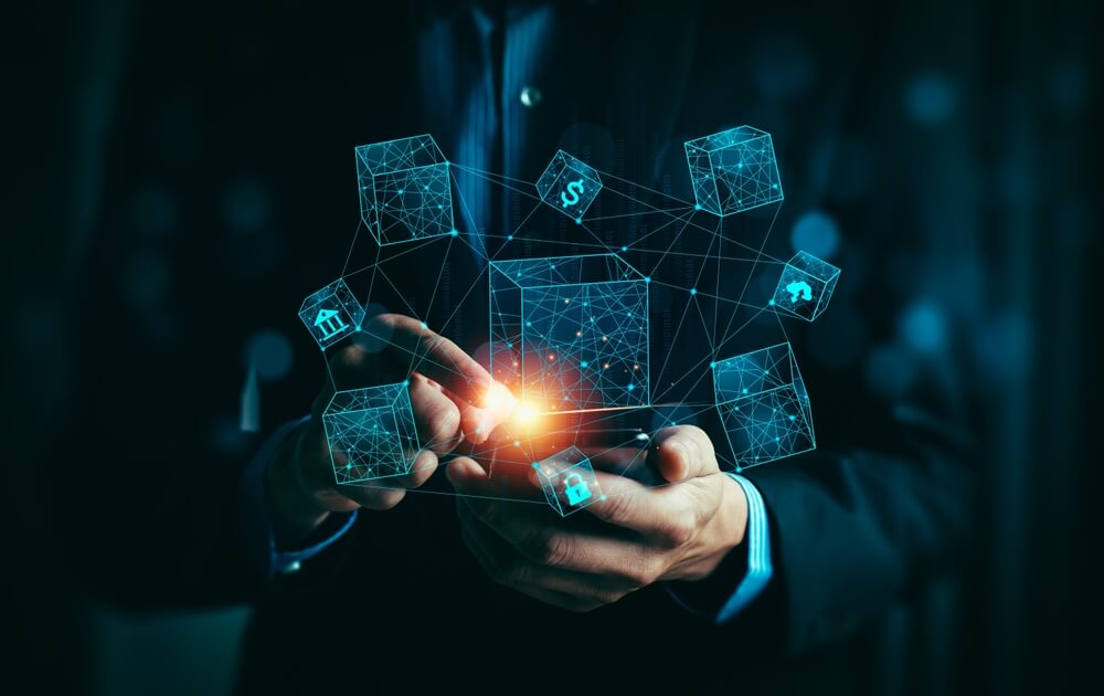 The image depicts a person holding a smartphone with a glowing point of light emanating from it, surrounded by interconnected cubes with various icons representing different aspects of technology and business, such as security, finance, and communication. This visual metaphor highlights the importance of Application Maintenance Support Services in ensuring the seamless operation, optimization, and future-proofing of business applications in a digital environment