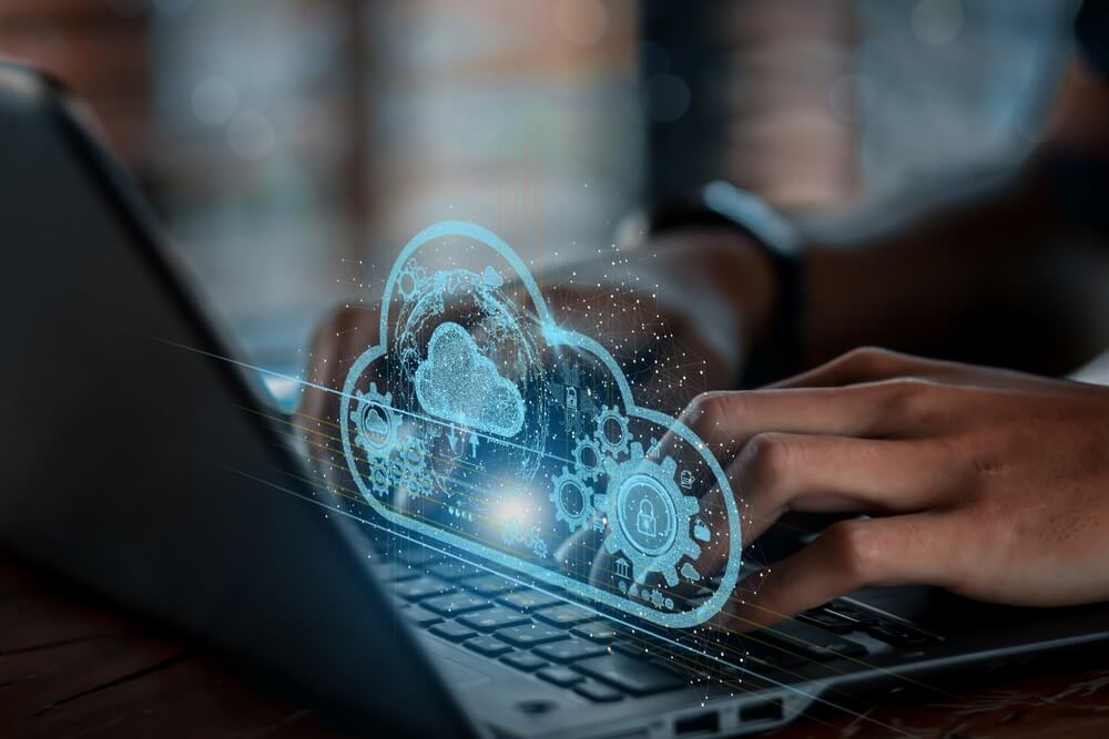 A person types on a laptop with various digital icons floating around, including symbols for the Internet of Things (IoT), cloud storage, security, and coding. This image represents the integration of Cloud Optimization Services in modern IT infrastructures, highlighting the importance of efficient cloud management in today's dynamic digital landscape.