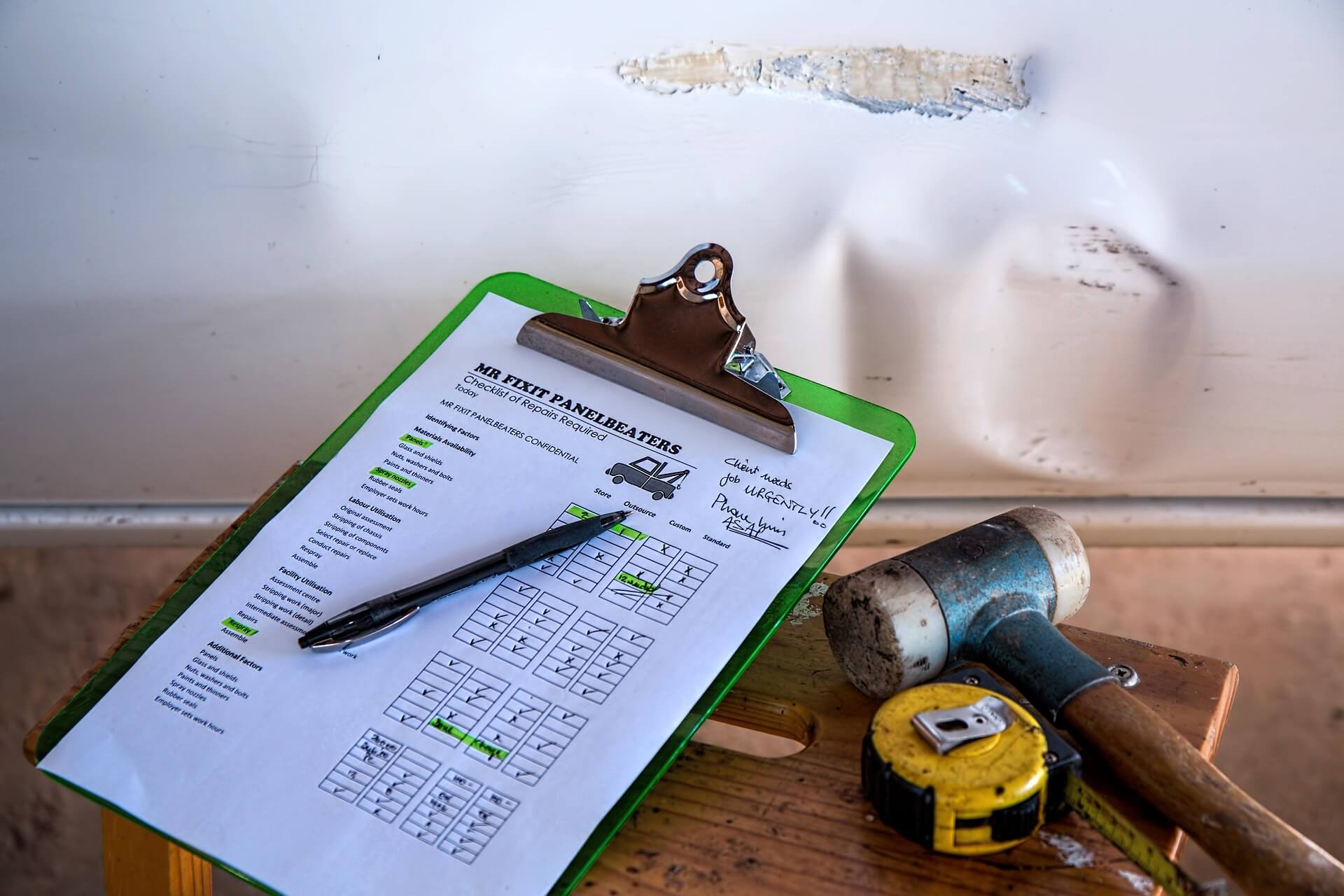 Reinsurance Assessment: A clipboard with a checklist, pen, hammer, and measuring tape on a wooden surface, illustrating Prima Consulting's Approach to Reinsurance Assessment.