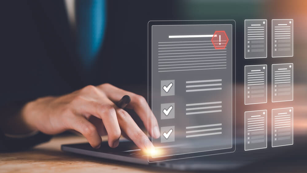 Policy Documentation: A person typing on a laptop with a digital overlay of a document checklist and warning icon, representing policy documentation and risk management.