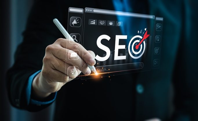 A person using a stylus to interact with a digital interface displaying the word "SEO" with a target icon, representing an SEO strategy.