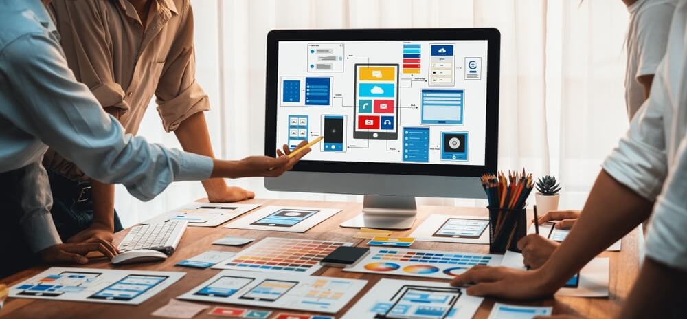 Website Development team collaborating on a project, with a computer screen displaying a website wireframe.