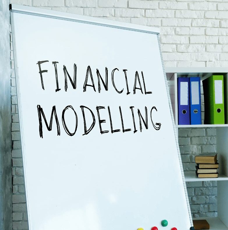 A whiteboard with "Financial Modelling" written on it, placed in an office setting with books and binders. Financial Modeling Services help businesses make data-driven decisions and avoid risks with accurate financial insights.