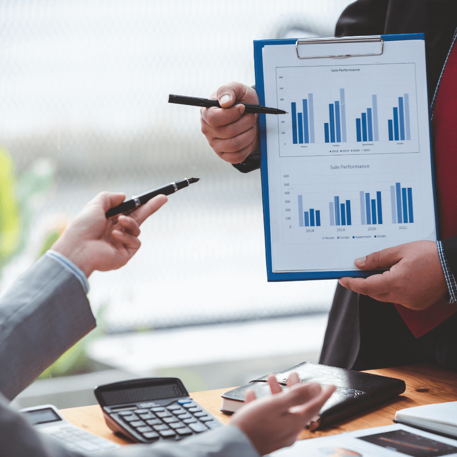 A business discussion on Feasibility Studies, with professionals analyzing sales performance charts on a clipboard.