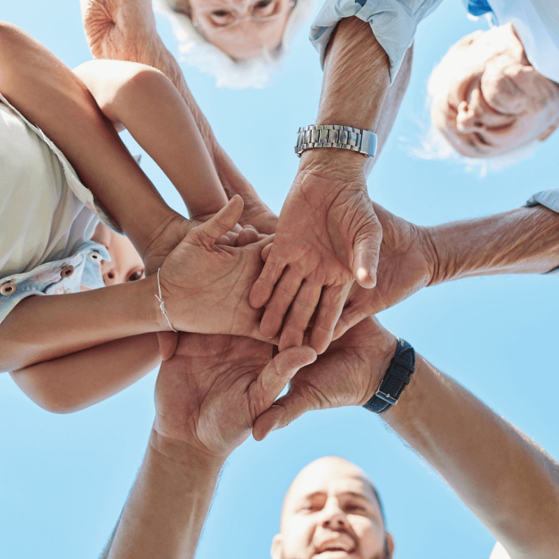 A multi-generational family circle joining hands in unity, symbolizing strong family bonds and teamwork.