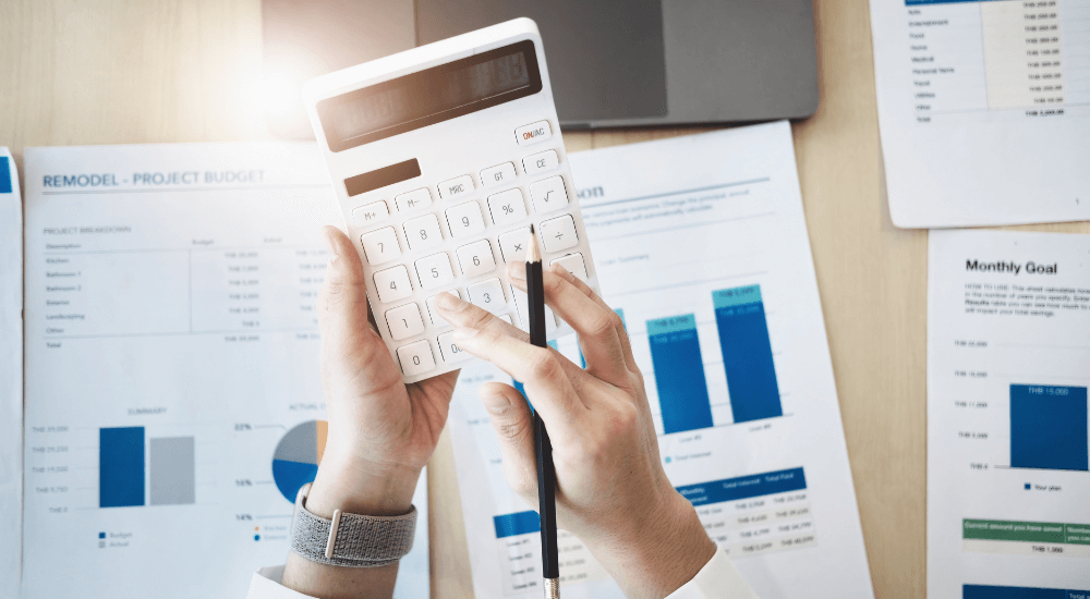 A person using a calculator above financial documents, highlighting the need for ARK9 EIR IFRS 9 compliance software to avoid manual EIR calculation errors.