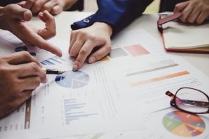 Close-up of hands pointing at financial charts and documents during a meeting focused on IFRS 2 advisory.