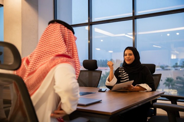 A professional meeting in a modern office with a person in traditional attire and another holding a tablet, discussing IFRS 2 advisory.