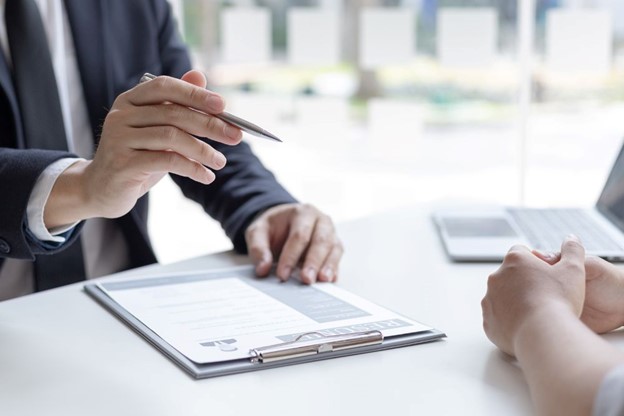 Discover actuarial valuation services through a professional client meeting, featuring a clipboard with documents and a pen in a modern office setting.