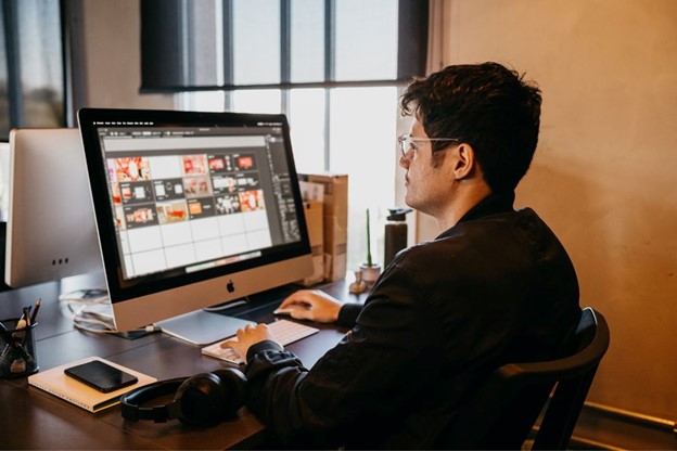 A designer working on a computer with multiple screens displaying IFRS 17 implementation data and graphics.
