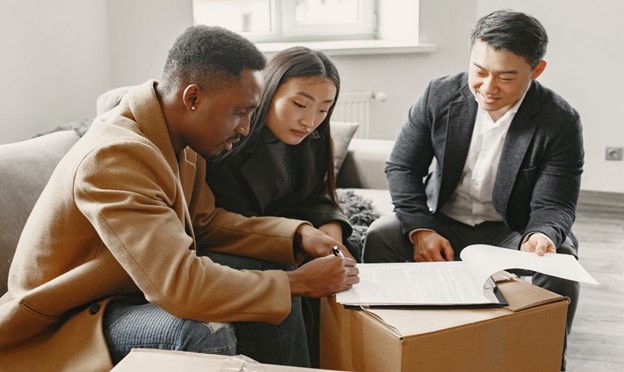 Three individuals signing documents related to IFRS 15 revenue from contracts with customers, seated around a box in a meeting.