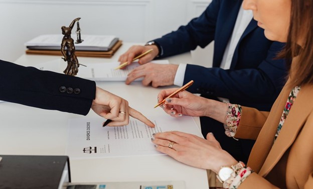 Professionals reviewing an IFRS 15 revenue from contracts with customers document with a scales of justice statue in the background.