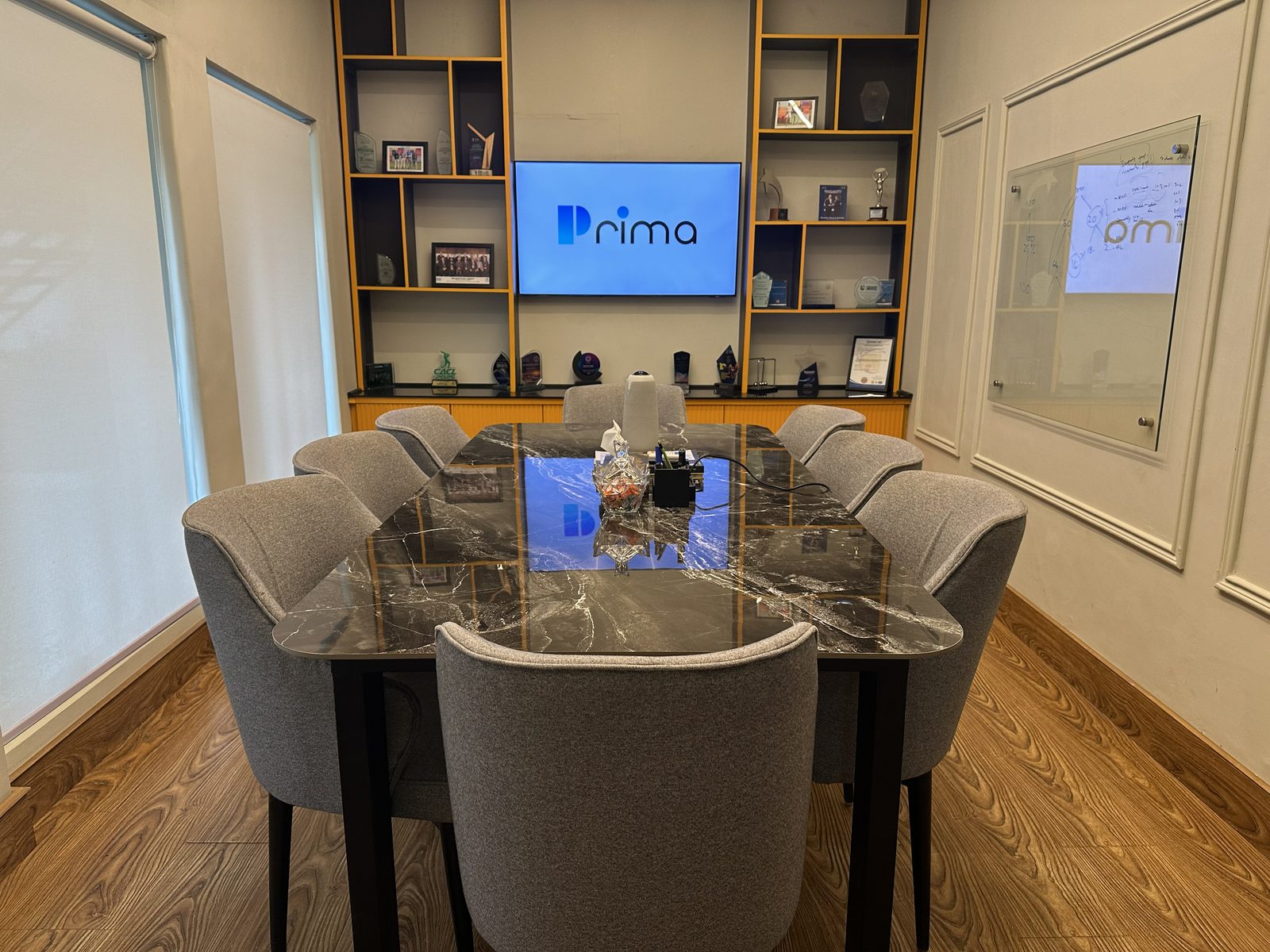 Conference room at one of our offices, with the Prima logo on screen and client awards on the shelves